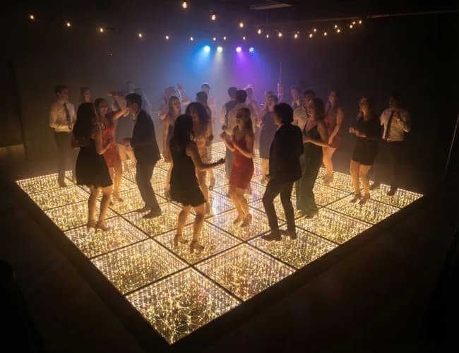 Mirrored star LED dance floor glowing warm white with guests around it