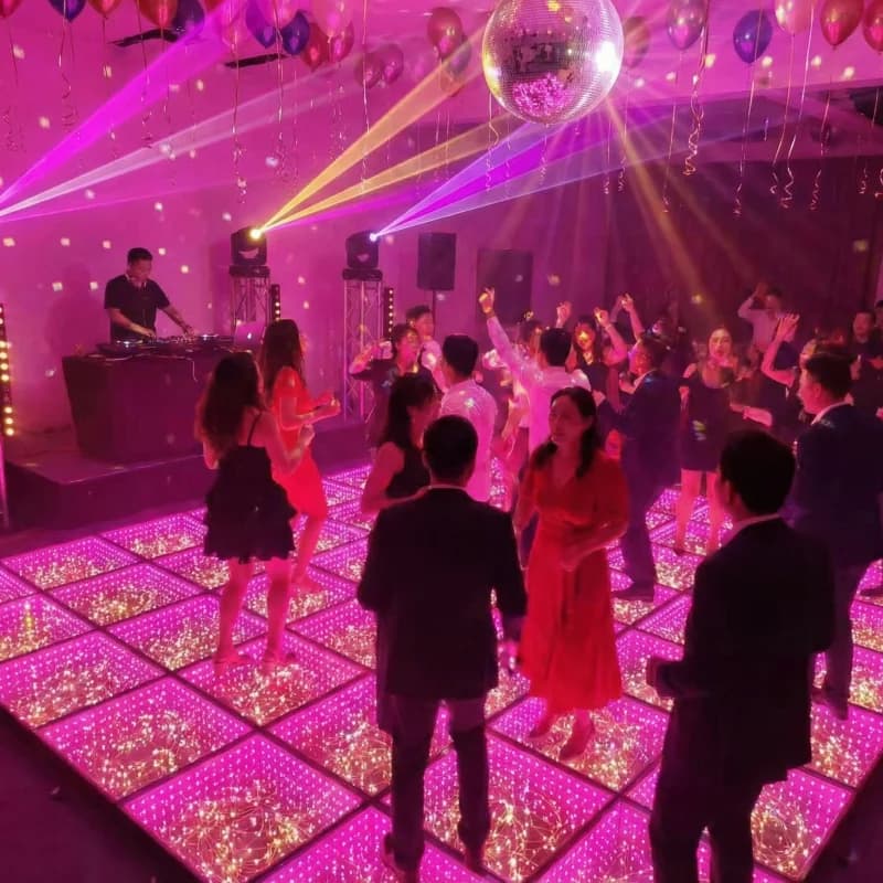 Mirrored star LED dance floor illuminated pink in a party setting